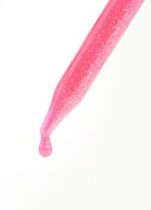 ピンク色のスポイトから落ちる美容液のしずく